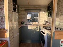Uma cozinha compacta com janela, pia, fogão e armários.