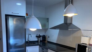 A modern kitchen with stainless steel appliances, a white dining table, and pendant lighting. - Ground floor Aqua Nature La Mata Costa Blanca (La Mata)