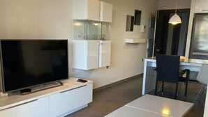 A modern kitchen with a flat-screen TV, white cabinetry, and a dining area with a table and chairs. - Ground floor Aqua Nature La Mata Costa Blanca (La Mata)