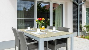 Une table à manger avec des chaises, un vase de fleurs et un saladier de fruits.