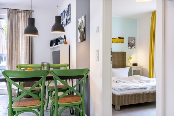 Une chambre d’hôtel moderne, équipée d’un lit, d’un coin repas avec une table et des chaises, et offrant une vue sur l’extérieur.
