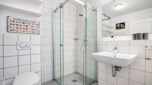 Une salle de bain moderne avec une douche à parois de verre, un lavabo blanc et des toilettes.