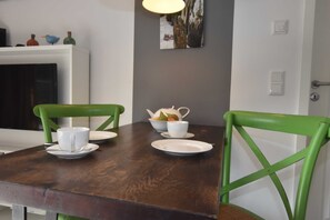 Et spisebord med stole, en skål med frugt og en hvid kop.