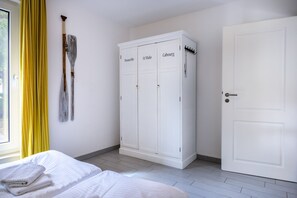 Quarto com uma cama, um guarda-roupa branco e uma porta.