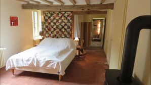 A bedroom with a bed, a radiator, a wooden chair, a lamp, and a fireplace. - Historic 18th Century Home with Modern Comforts in Medieval Village (Montmirail)