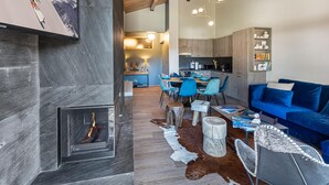 Un salon moderne avec une cheminée, un canapé bleu et un coin repas avec des chaises bleues.
