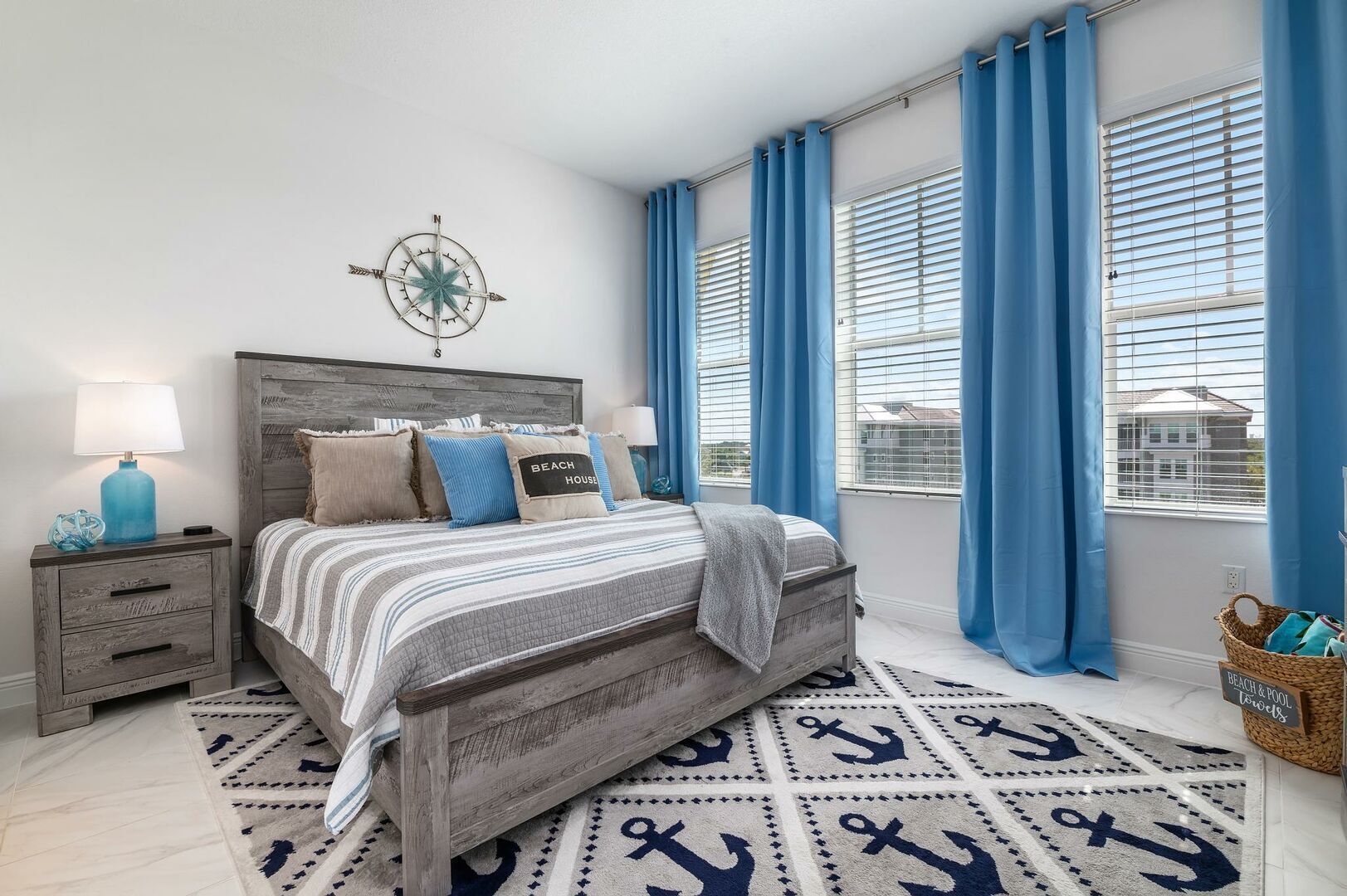 Un dormitorio con cama, mesitas de noche, decoración de pared con brújula y detalles marineros.