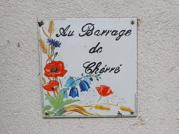 A ceramic tile with 'Au Barrage de Chêne' text and floral designs. - Troglodyte house with WiFi, barbecue, and fireplace (Aubigné-Racan)