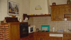 A kitchen with wooden cabinets, a brick wall, a microwave, and a stove.