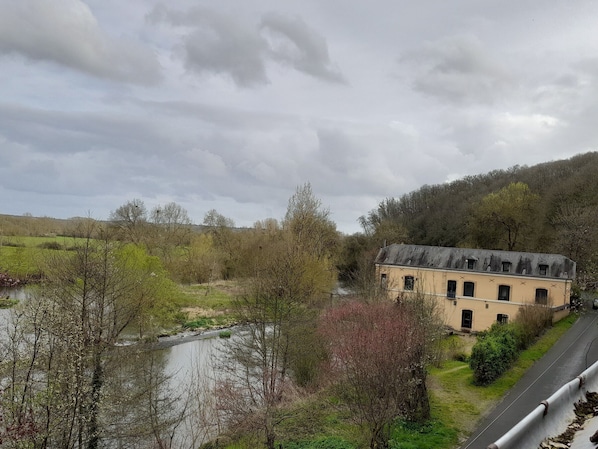 Een gebouw met een schuin dak, een verharde weg ernaast en een rivier op de voorgrond.