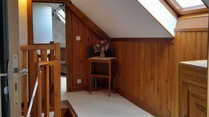 A wooden interior with a skylight, a staircase, and a small table with flowers.