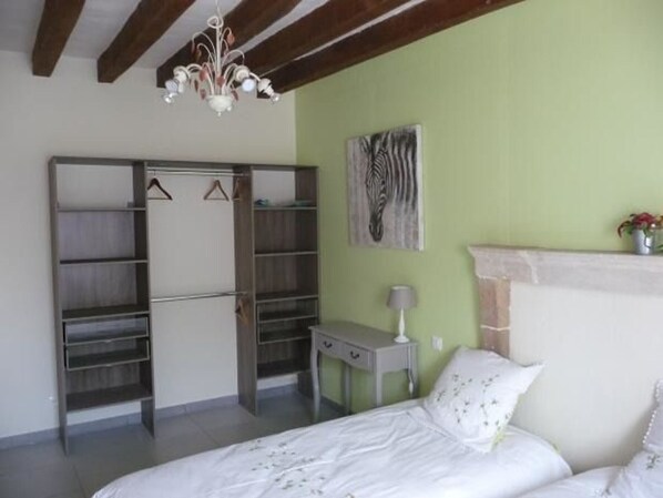 A bedroom with a bed, a wardrobe, a desk, a lamp, and a zebra painting on the wall. - Cozy Cottage Near Le Mans: 3 BR, Full Kitchen, Close to 24H Circuit, Sleeps 6 (Moncé-en-Belin)
