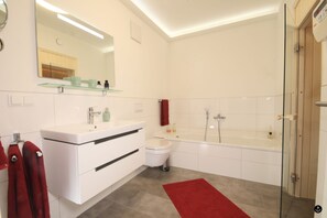 Une salle de bain moderne avec une douche à parois de verre, un meuble-lavabo blanc avec un miroir et un tapis de bain rouge.