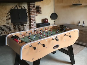 Ein Fußballtisch in einem Raum mit einer Ziegelwand und einer hängenden Pfanne.