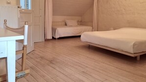 Une chambre avec un lit simple, une petite table et une fenêtre avec des rideaux.