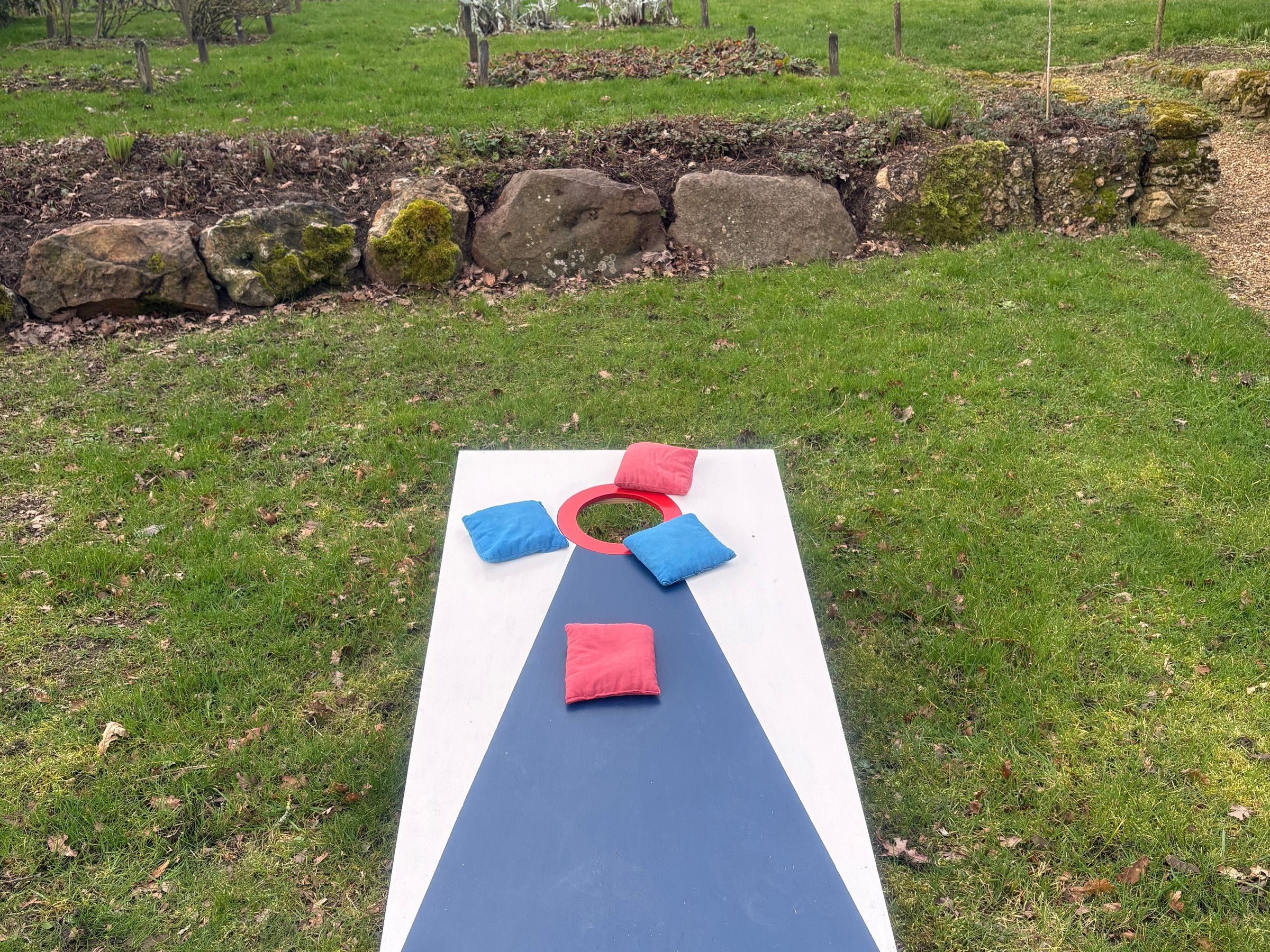 Un'area picnic con una coperta, cuscini e un anello sull'erba.