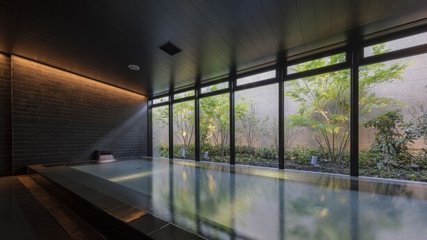 A modern indoor pool with large windows, a brick wall, and a wooden ceiling. - THE BLOSSOM KUMAMOTO (Kumamoto)