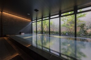 A modern indoor pool with large windows, a brick wall, and a wooden ceiling. - THE BLOSSOM KUMAMOTO (Kumamoto)