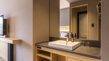 Un baño moderno con un espejo grande, un lavabo blanco y un mueble de tocador de madera.