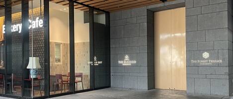 A modern building with glass doors and a wooden ceiling. There are signs for 'The Blossom' and 'The Forest Terrace'.