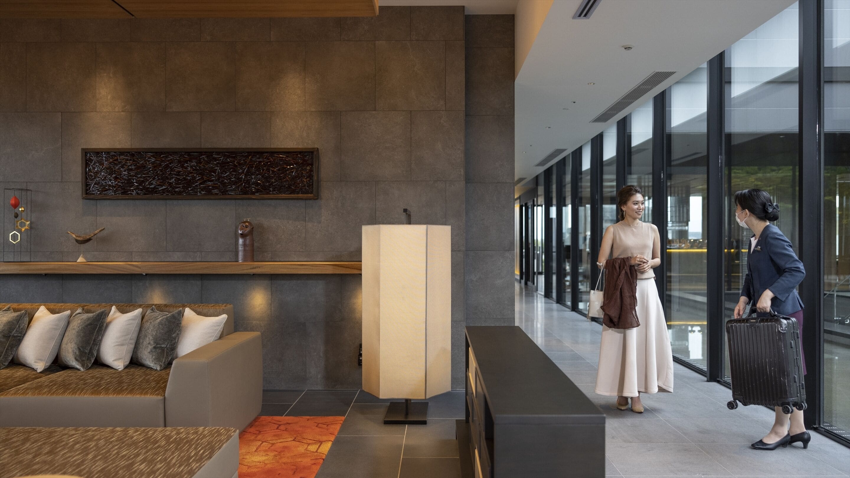 A modern lobby with a reception desk, seating area, and large windows.