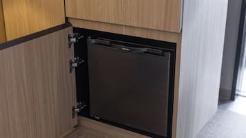 A compact, built-in dishwasher in a kitchen with wooden cabinetry.