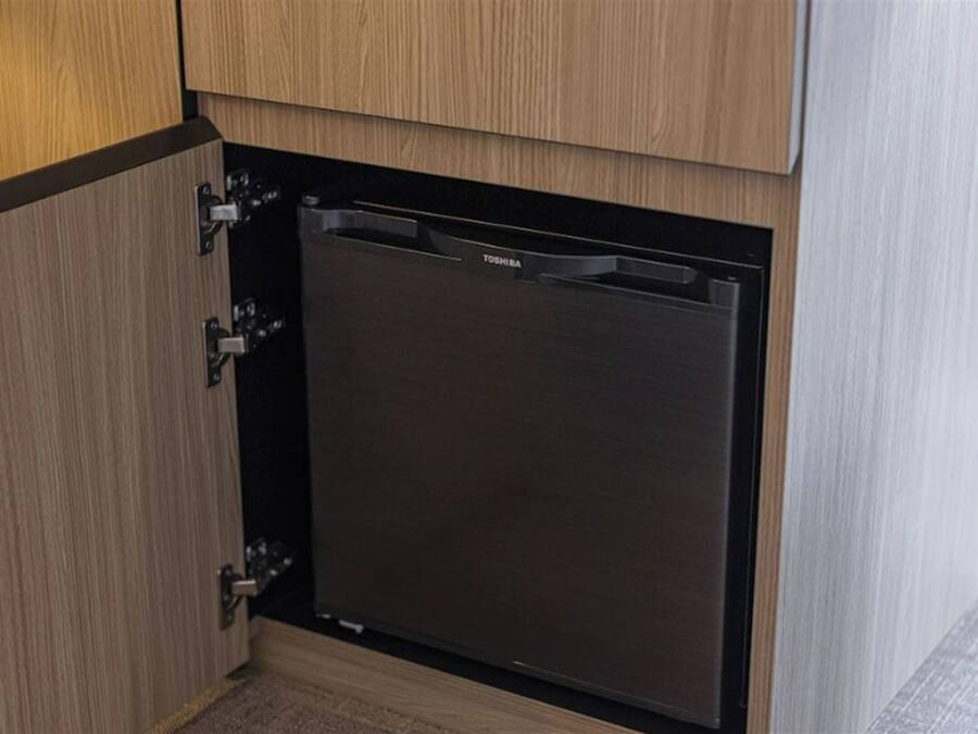 A compact, built-in dishwasher in a kitchen with wooden cabinetry.