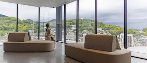 A spacious room with large windows offering a city view, two sofas, and a ceiling with recessed lighting.