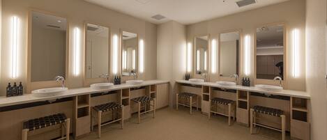A modern bathroom with two sinks, large mirrors, and wooden benches.