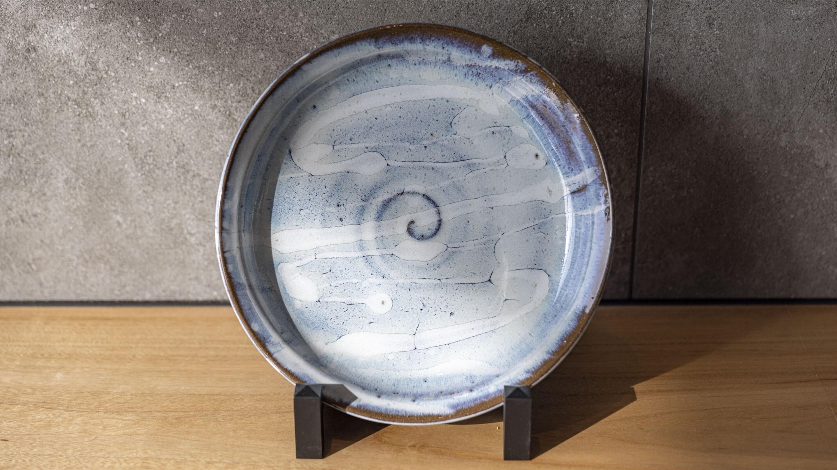 A ceramic plate with a spiral design on a stand.