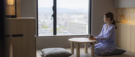 Una persona sentada en un banco junto a una ventana con vistas a la ciudad.