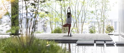 A person performing yoga on a rooftop terrace with a cityscape view.