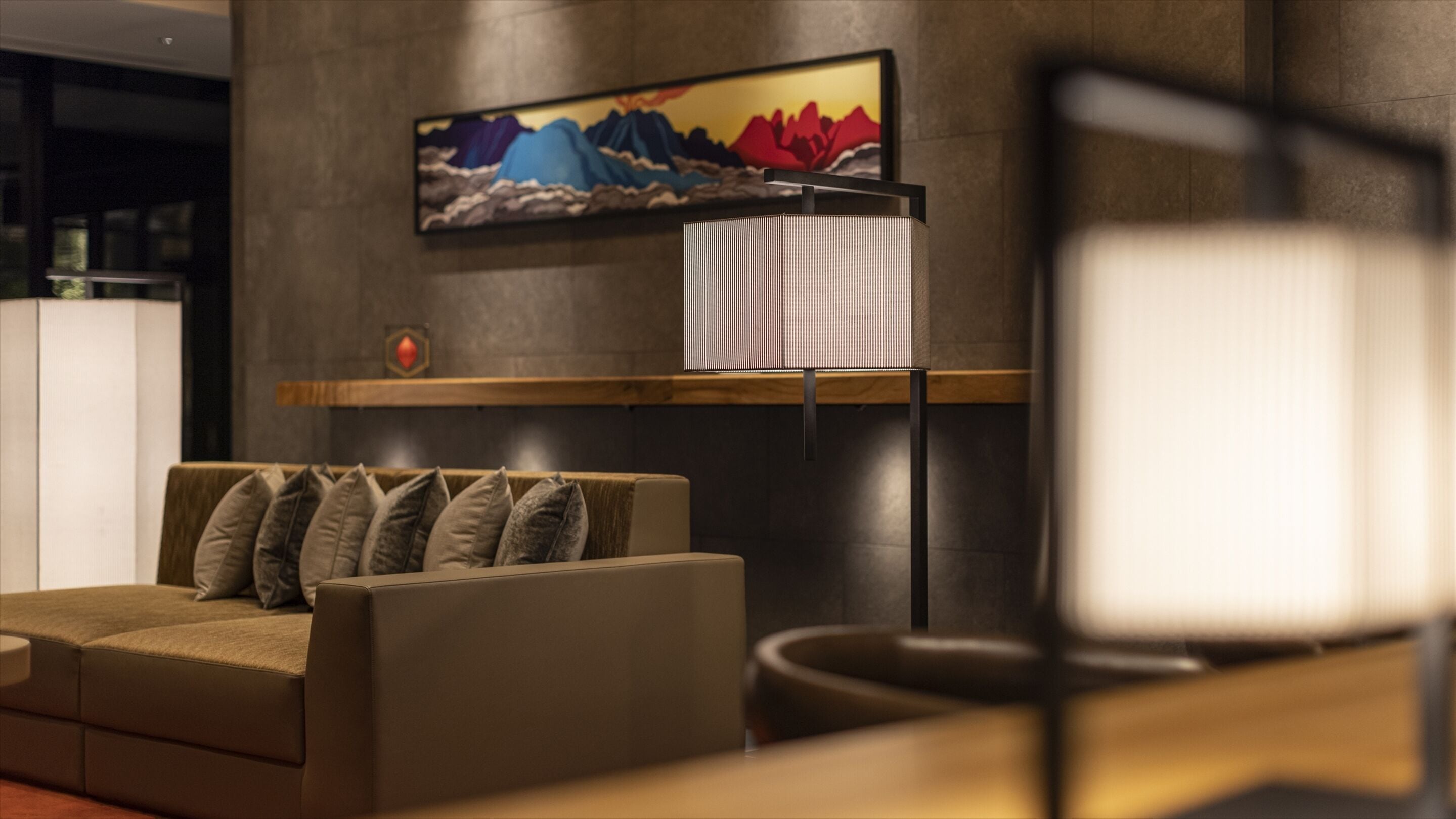 A modern living room with a sofa, a wall-mounted TV, and a decorative shelf.