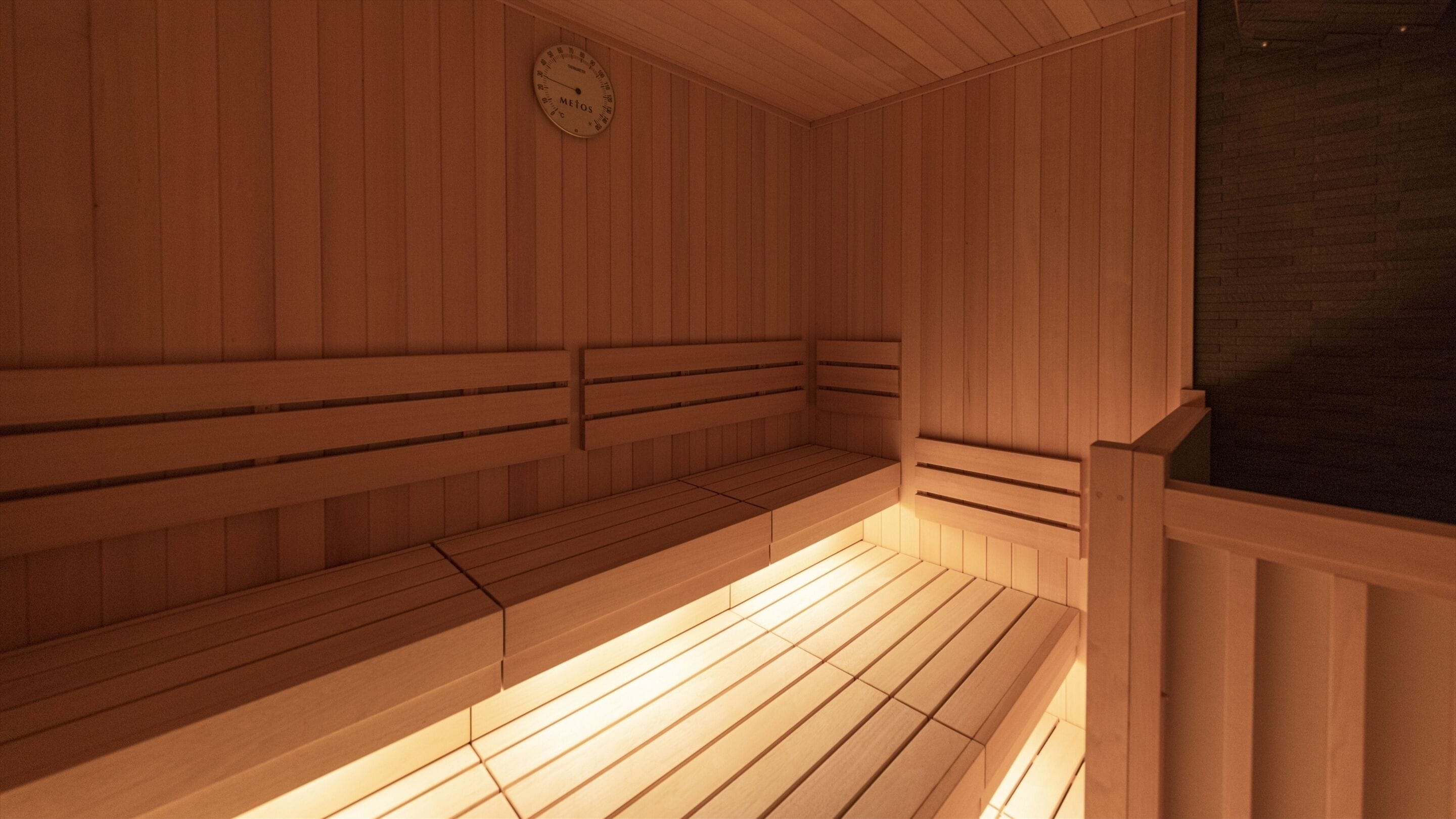 Un sauna avec des bancs en bois et une horloge bien visible au mur.