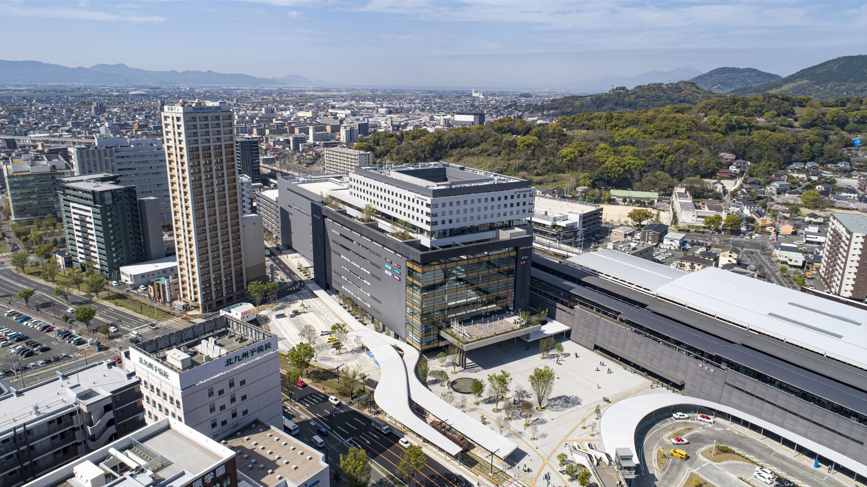 Un quartier urbain moderne, caractérisé par de grands immeubles, une place centrale et de nombreux espaces verts environnants.