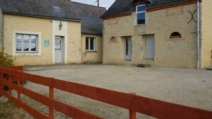 A building with a gravel courtyard, a wooden fence, and a door with a sign.