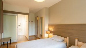 A hotel room with two beds, a desk, and a door leading to a bathroom.