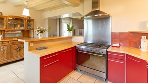 A kitchen with red cabinets, a stainless steel stove, and wooden countertops.