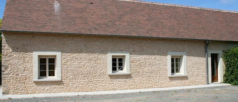 Un edificio in pietra con tetto a tegole, due finestre e una porta.