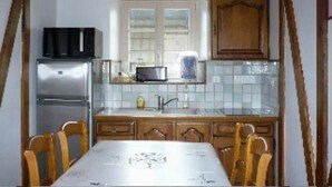 Une cuisine équipée d’un réfrigérateur, d’un four à micro-ondes et de meubles de rangement en bois.