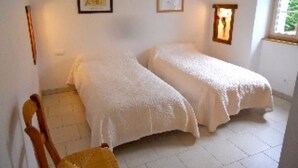 Une chambre avec deux lits, une chaise et une fenêtre.