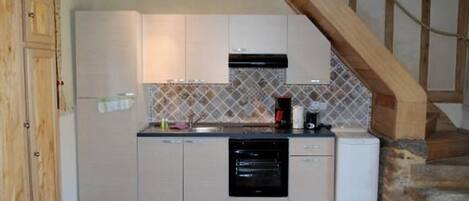 A kitchen with white cabinets, a black oven, and a tiled backsplash.