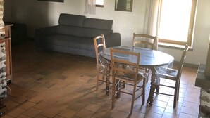 Een woonkamer met een bank, een eettafel met stoelen en een raam met gordijnen.