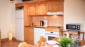 Una cocina compacta con armarios de madera, un microondas, una cafetera y un lavavajillas.