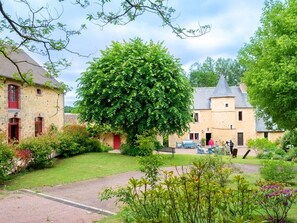 A traditional stone building with a large tree in front, a paved driveway, and a grassy area with a bench. - Charming Countryside Cottage with River Views, Near Historic Manor House (Asnières-sur-Vègre)