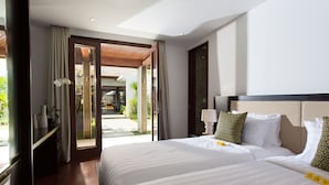 A hotel room with a large bed, a nightstand, a lamp, and a view of the outdoor area. - Villa Lilibel (Seminyak)