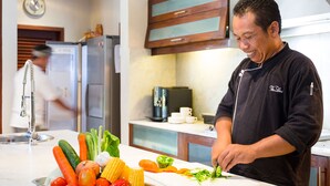 A kitchen with a person preparing vegetables on a cutting board. - Villa Lilibel (Seminyak)