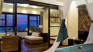 Un dormitorio con cama, una silla, un escritorio y un ventanal grande.