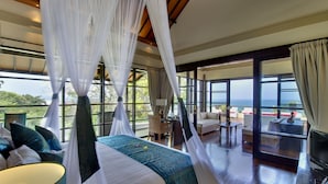 Un dormitorio con cama a dosel, ventanas amplias y vista al mar.