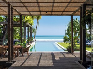 Una terraza de madera con piscina y sillas de descanso con vista al océano.